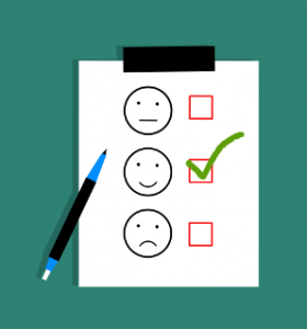 Three smiley faces on a piece of paper with checkboxes next to them and a checkmark in the middle smiling one