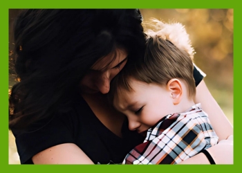 A light skinned dark haired woman holding a light skinned brown haired young boy in her arms