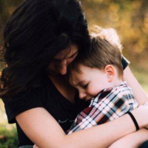 A light skinned dark haired woman holding a light skinned brown haired young boy in her arms